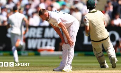 England bowler Gus Atkinson bends over to hold is legs with an apparent hamstring injury