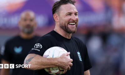 Brendon McCullum smiles with a football under his arm