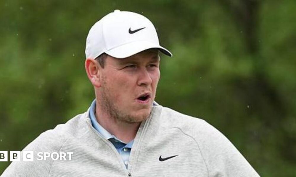 Robert MacIntyre in grey golf fleece and white cap during the final round of the Texas Open, with greenery in the background
