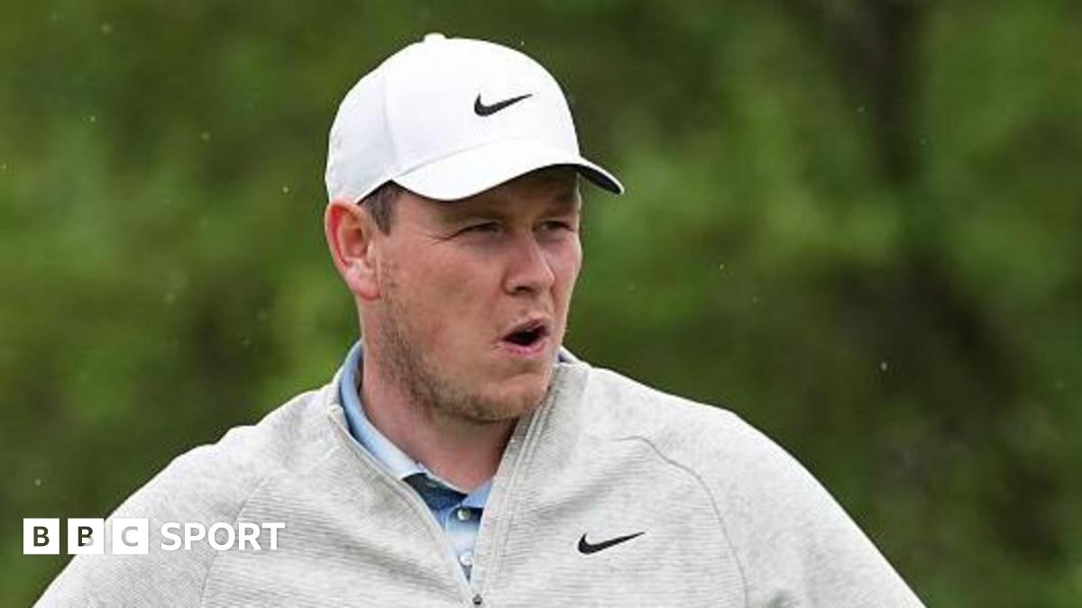 Robert MacIntyre in grey golf fleece and white cap during the final round of the Texas Open, with greenery in the background