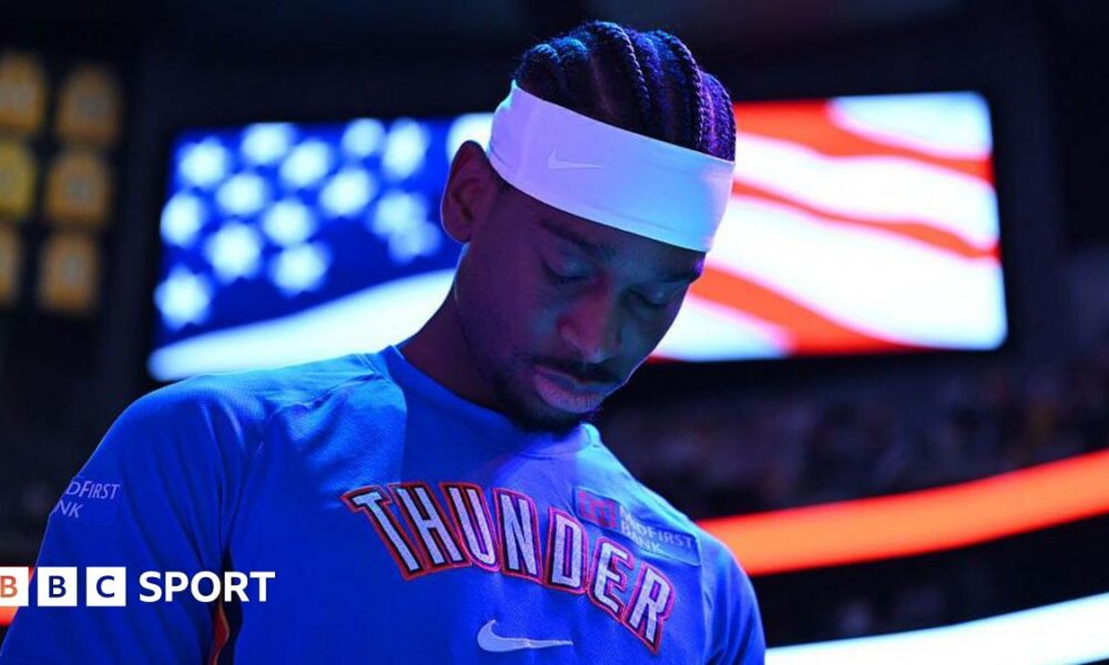 Shai Gilgeous-Alexander of Oklahoma City Thunder in a blue team leisurewear top and white headband, with his head bowed