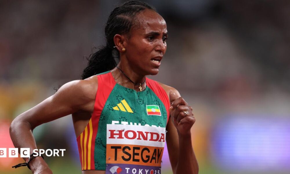 Gudaf Tsegay is seen from the waist up wearing an Ethiopia running vest with a bib with her surname and the Tokyo 2025 logo on the front of it. She looks foward in concentration while she runs