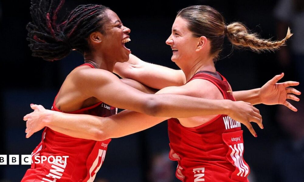 Fran Williams and Olivia Tchine, wearing England's red netball jersey, celebrate after beating South Africa to reach the semi-final by jumping in the air and hugging each other