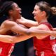 Fran Williams and Olivia Tchine, wearing England's red netball jersey, celebrate after beating South Africa to reach the semi-final by jumping in the air and hugging each other