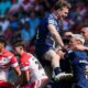 Toulouse players, in dark blue, celebrate a try against St Helens, two of whose players, in red and white, look disconsolate.