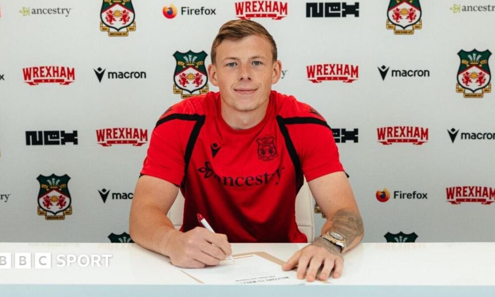 Wrexham's new goalkeeper Anthony Patterson signing papers at a desk