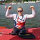 Charlotte Henshaw celebrates with her arms raised having just got out of her kayak