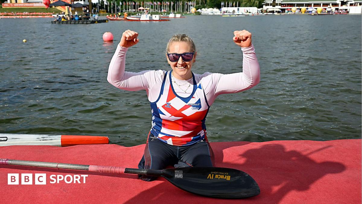 Charlotte Henshaw celebrates with her arms raised having just got out of her kayak