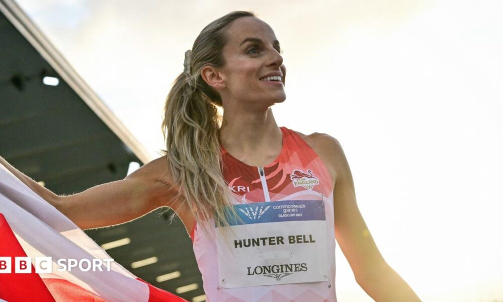 Georgia Hunter Bell smiles while unfurling an England flag