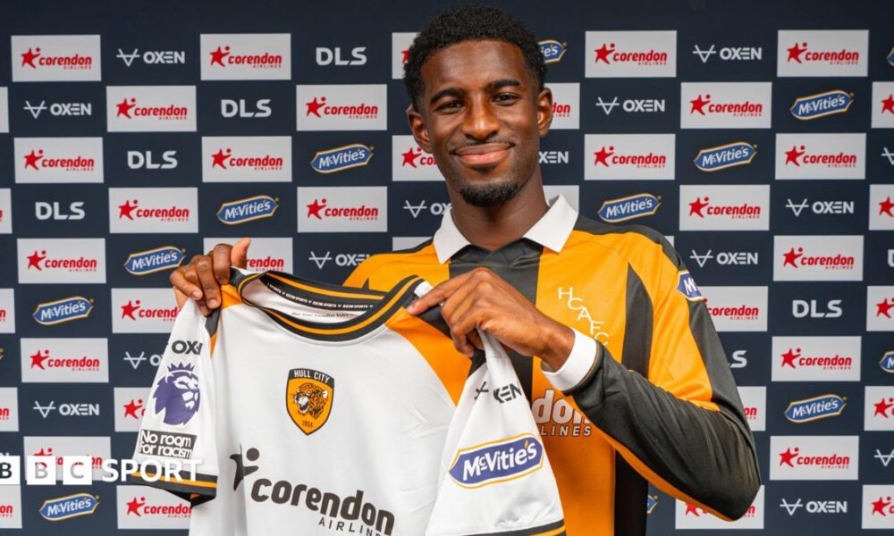 Hull City's new signing Mohamed-Ali Cho poses in the club's yellow and black home shirt, while holding up their white away strip