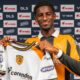 Hull City's new signing Mohamed-Ali Cho poses in the club's yellow and black home shirt, while holding up their white away strip