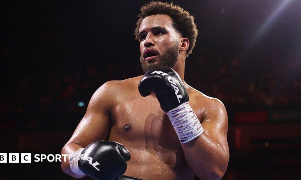 Moses Itauma holds up his hands and is wearing black boxing gloves