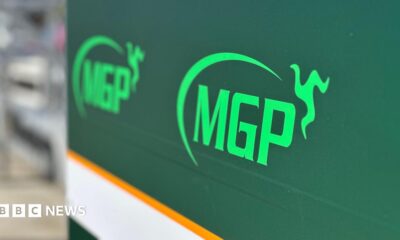 A large green sign with the MGP logo on it in pitlane.