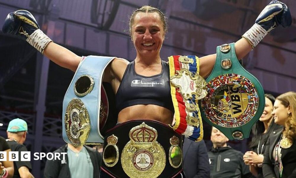Ellie Scotney smiles and stretches her arms wide as she shows off the WBO, WBA, IBF and WBC super-bantamweight belts