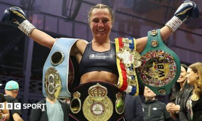 Ellie Scotney smiles and stretches her arms wide as she shows off the WBO, WBA, IBF and WBC super-bantamweight belts