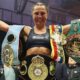 Ellie Scotney smiles and stretches her arms wide as she shows off the WBO, WBA, IBF and WBC super-bantamweight belts