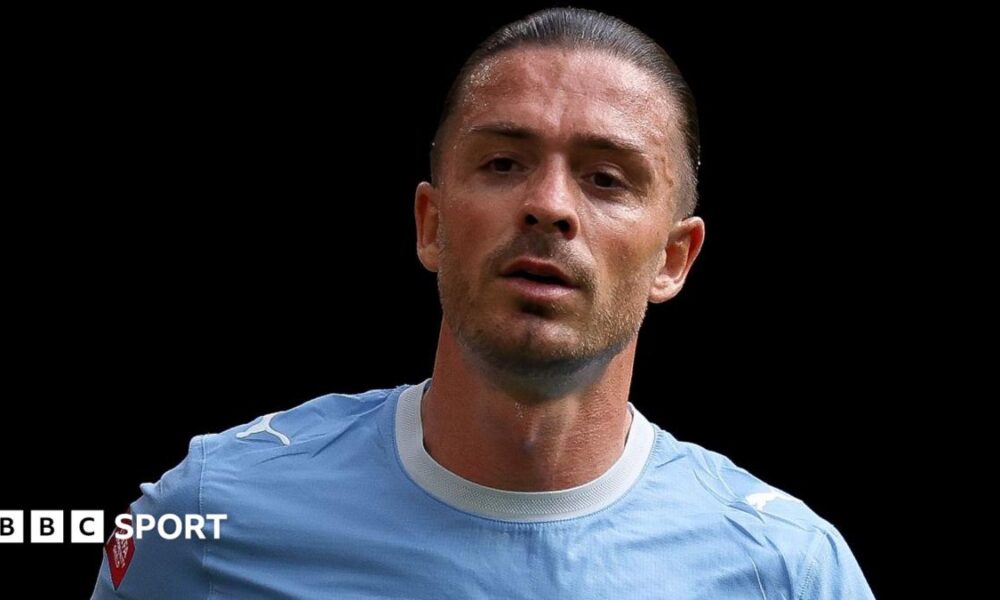 Jack Grealish, wearing Manchester City's sky blue kit, looks on during a match
