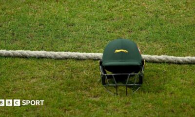 A green Leicestershire team helmet on the ground next to the boundary rope