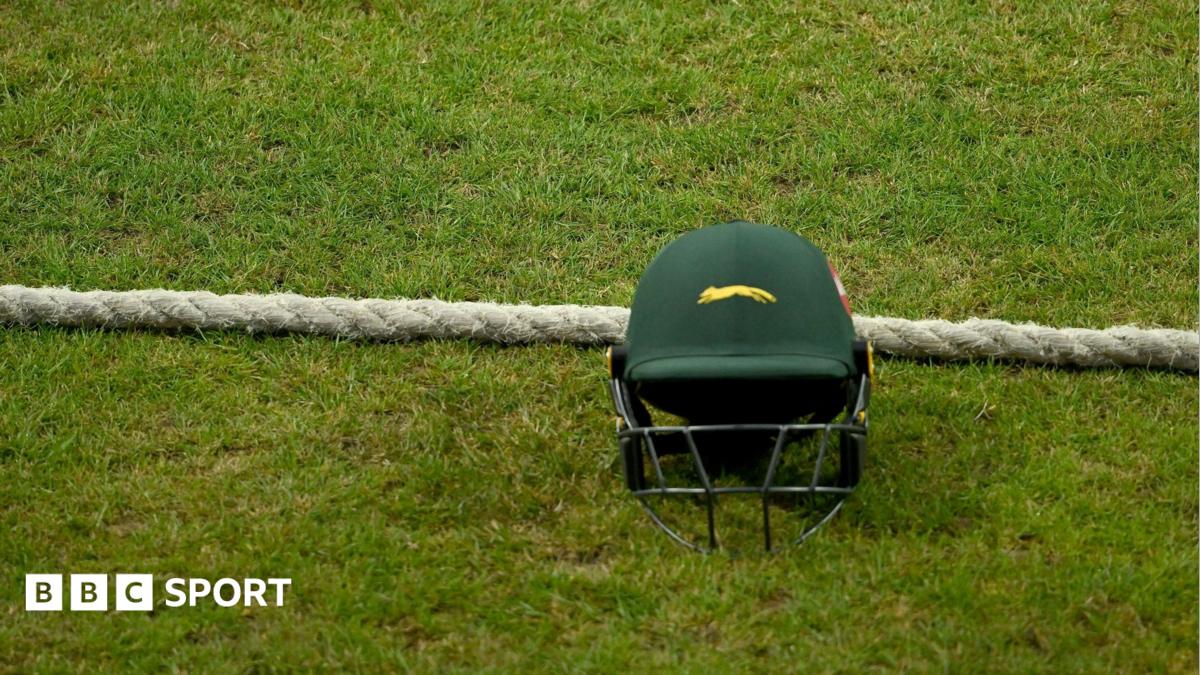A green Leicestershire team helmet on the ground next to the boundary rope