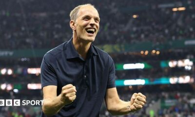 Thomas Tuchel, wearing a dark polo shirt, clenches two fists and grins in celebration